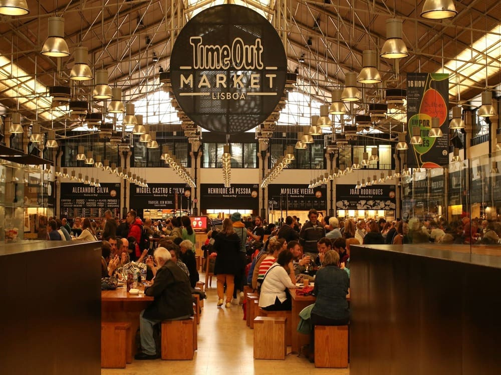 Interior of Time Out Market Lisbon with food stalls and people enjoying Portuguese cuisine
