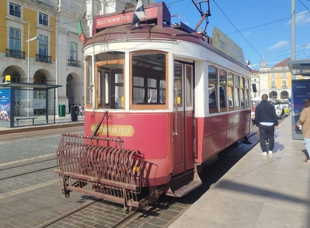A traditional Lisbon tram crossing Praça do Comércio, surrounded by grand yellow architecture and the wide open space facing the Tagus River.